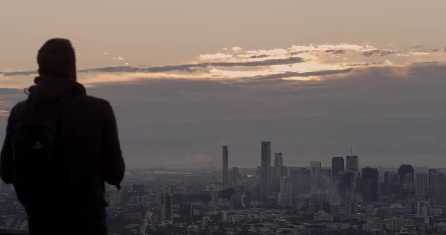 Man takes pictures on a hilltop of a distant city