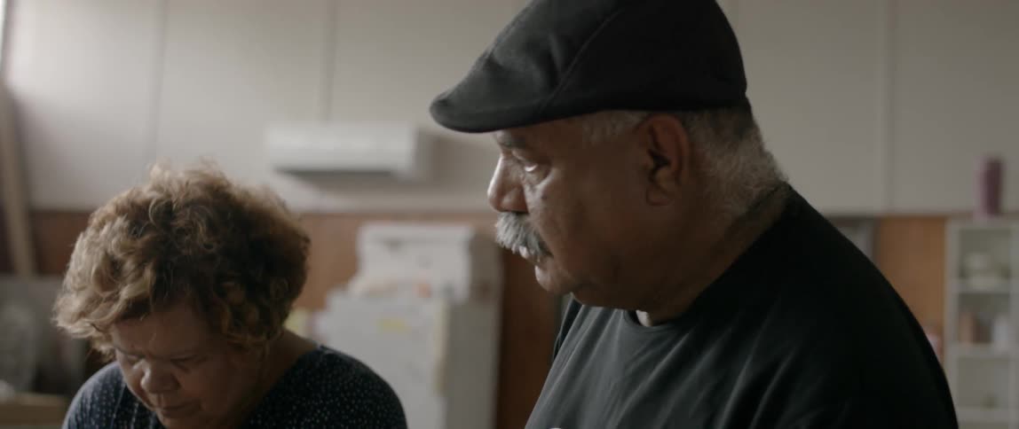 A man and woman stand together working on something