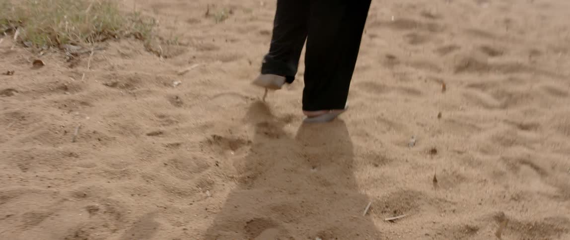 Person wearing flip flops walks on the sand