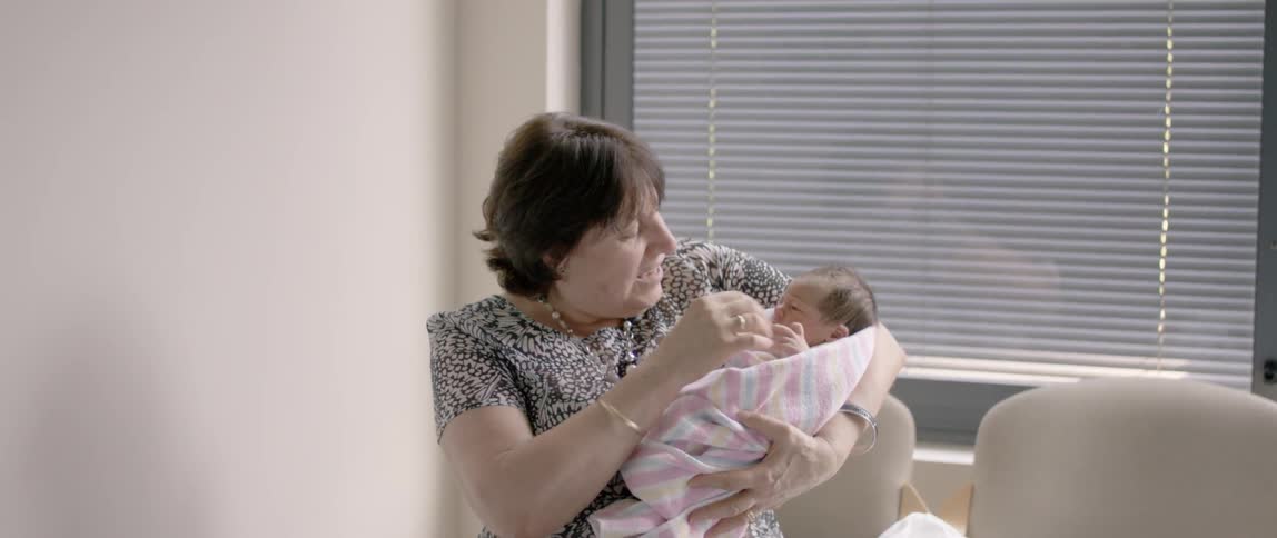 An older woman holds a newborn baby