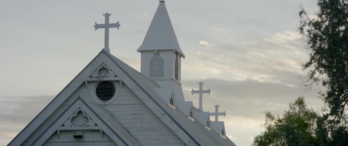 The church is lined with white crosses on a cloudy day