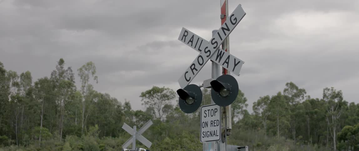 A railroad crossing sign is shown on a cloudy day