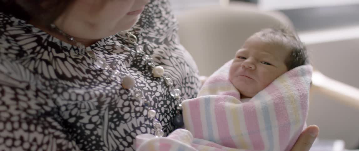 A woman smiles as she holds a baby