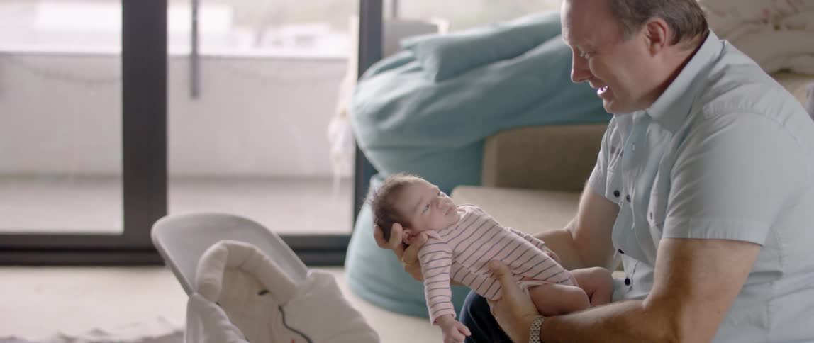 A baby holds a baby while sitting on a couch