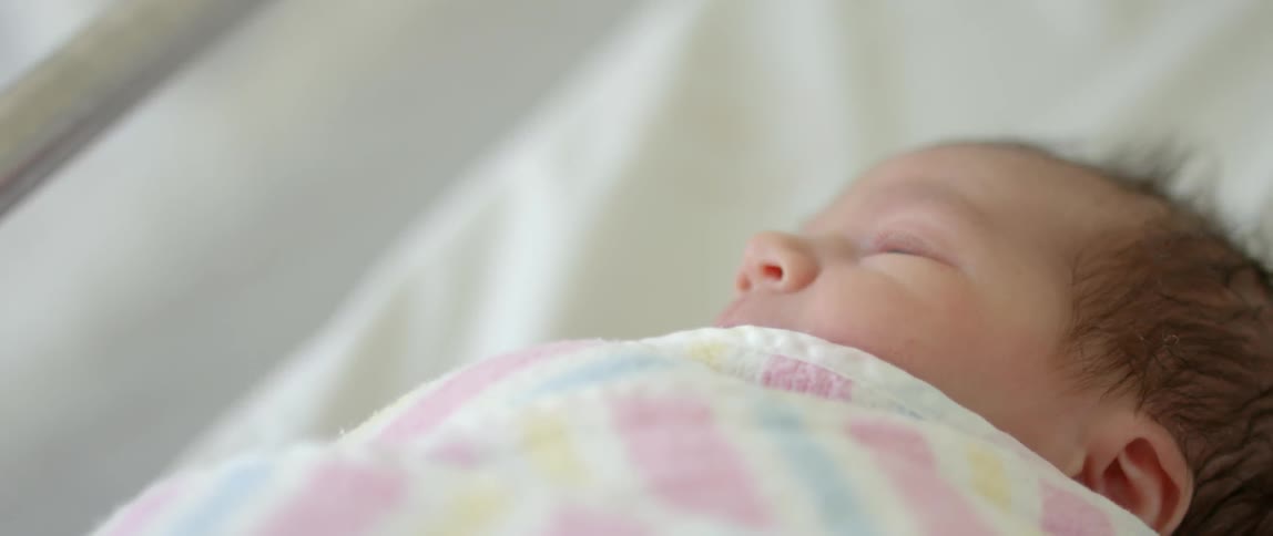 A baby is sleeping in a crib rolling around