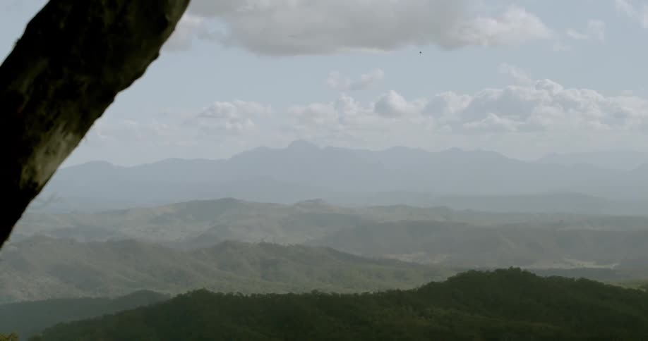 Clouds and haze hang over jungle covered hills