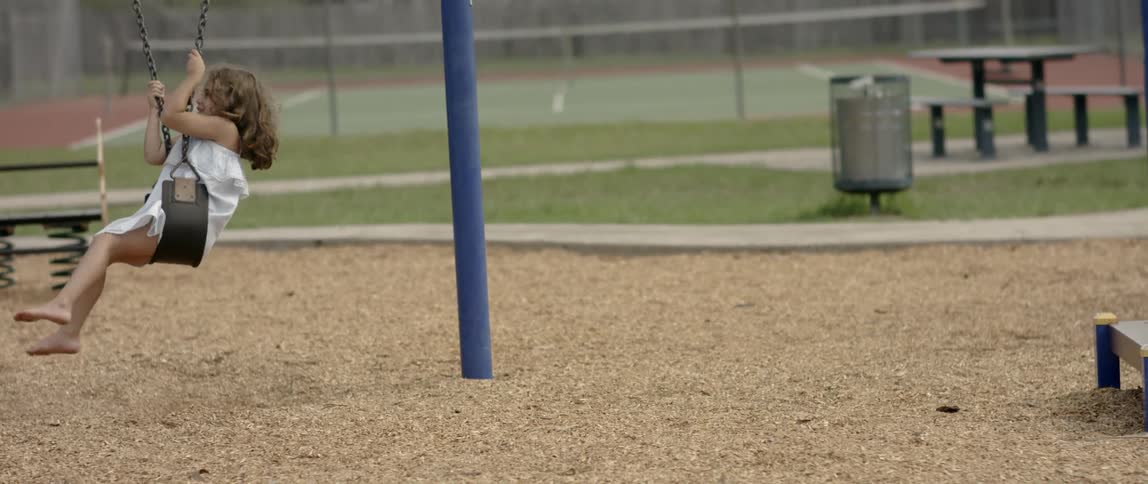 A young girl spins on a playground swing