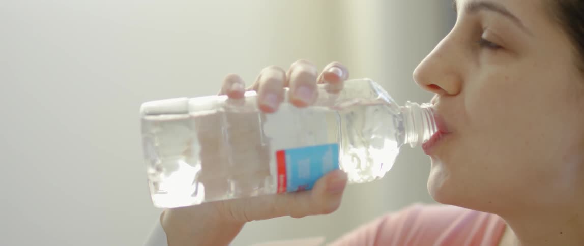 A woman takes a drink from a bottle of water