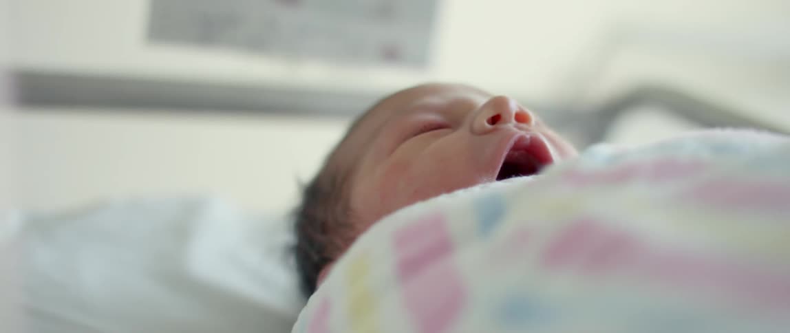 A personal checks on a swaddled newborn