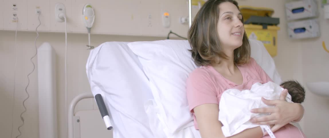 A newborn is held by its mother in a hospital bed