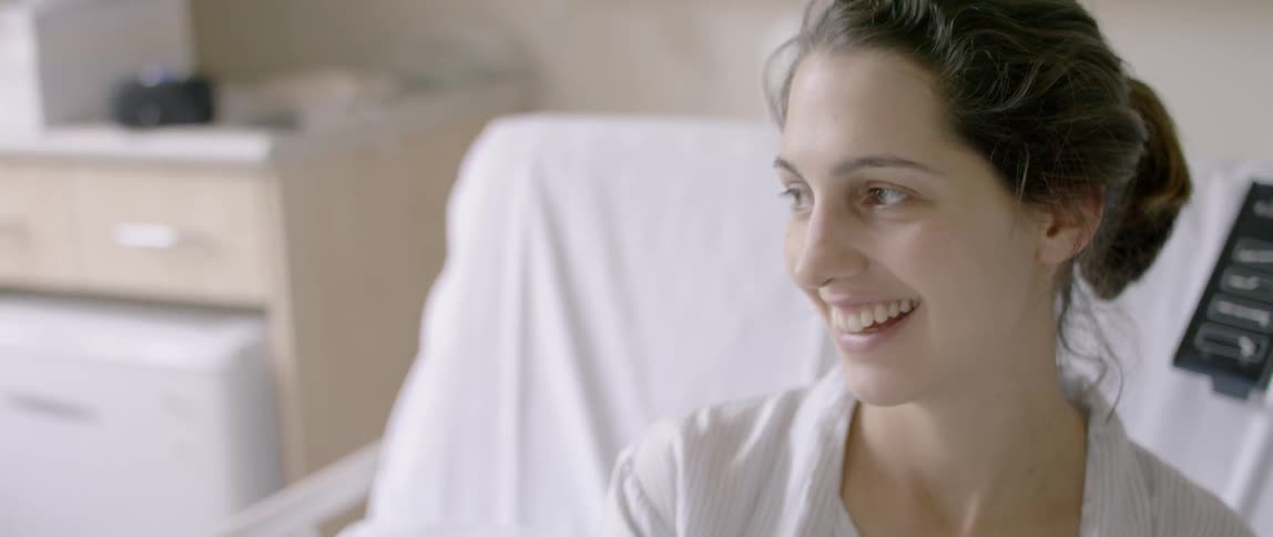 A woman smiles laying in a hospital bed