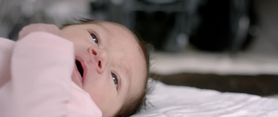 A baby lays in bed looking around