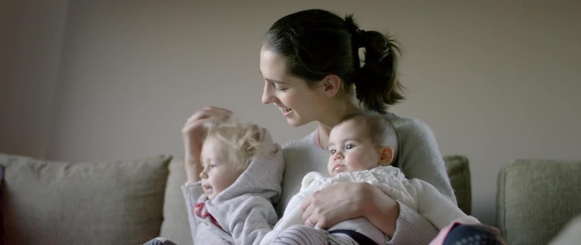 A woman smiles while sitting with three children on a couch