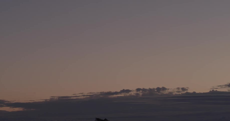 The sun is setting in the clear sky behind the clouds