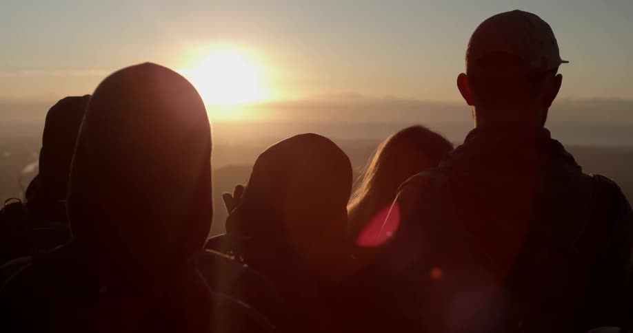 A group of people look out towards the bright sun