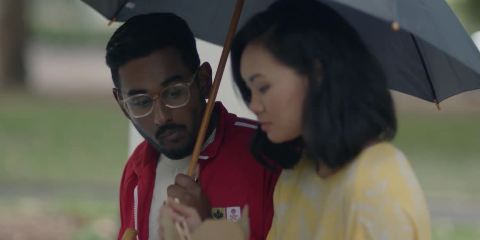 A man and woman eat under an umbrella