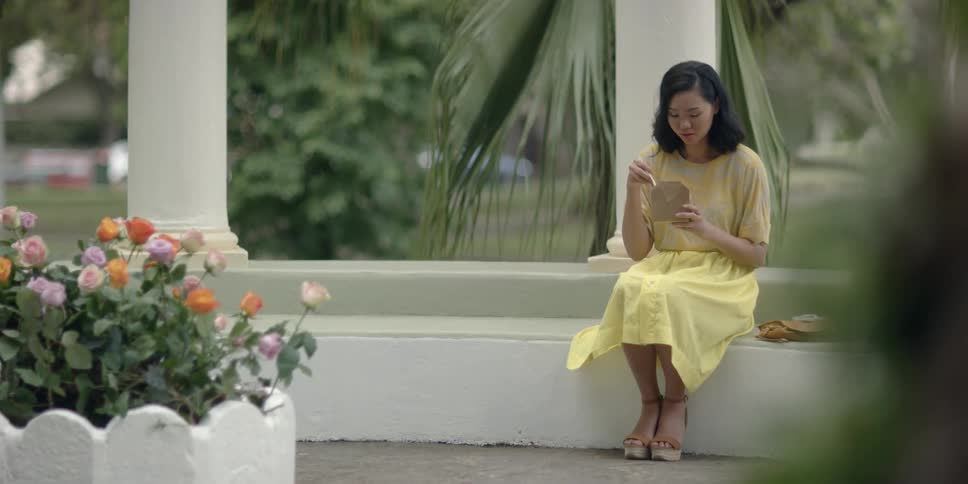 A woman eats outdoors with chopsticks