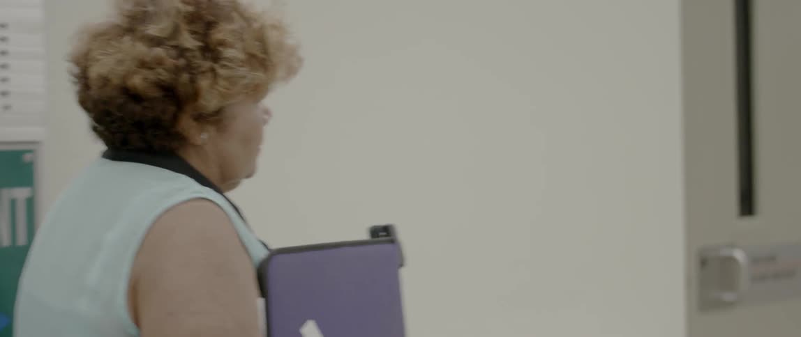 A woman walks down a hallway with a binder