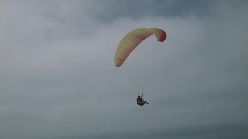 A person is parasailing on a cloudy day