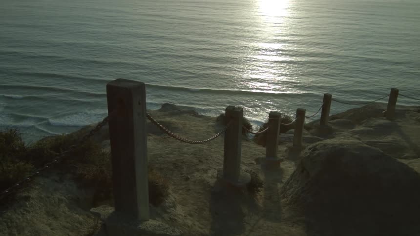 A rocky coastline near a wooden and rope fence