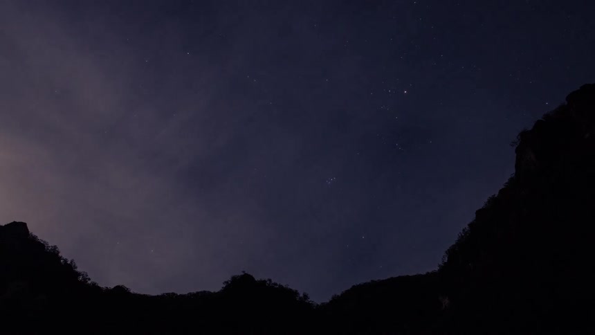 Timelapse view of clouds above a mountain as the day transitions from dusk to night