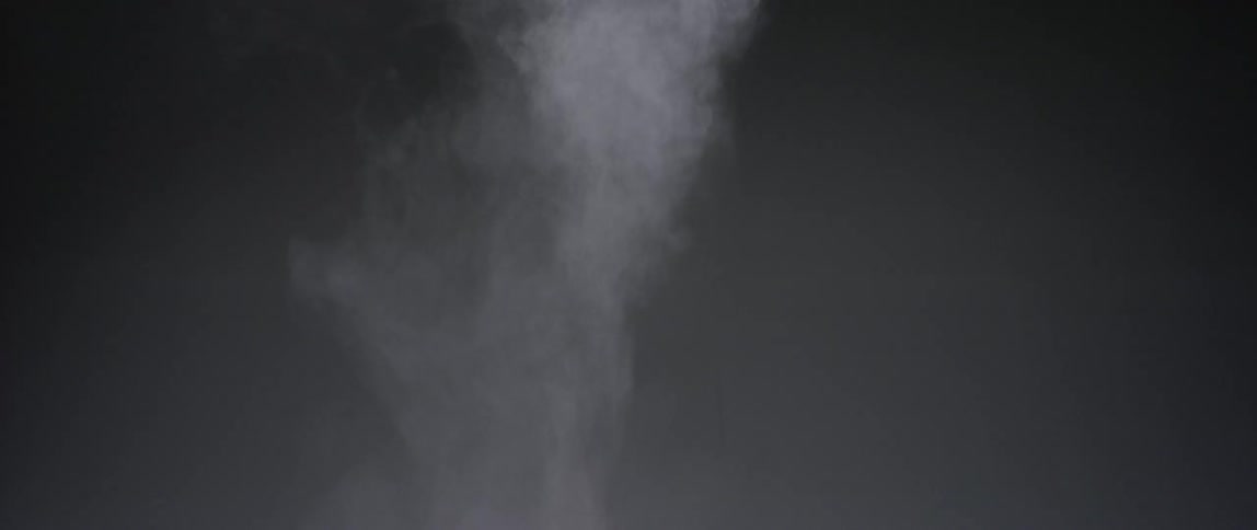 Smoke is being blown against a grey wall