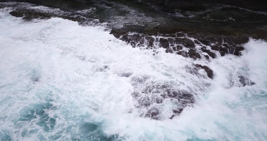 Large waves start to cover the rocks near the shore