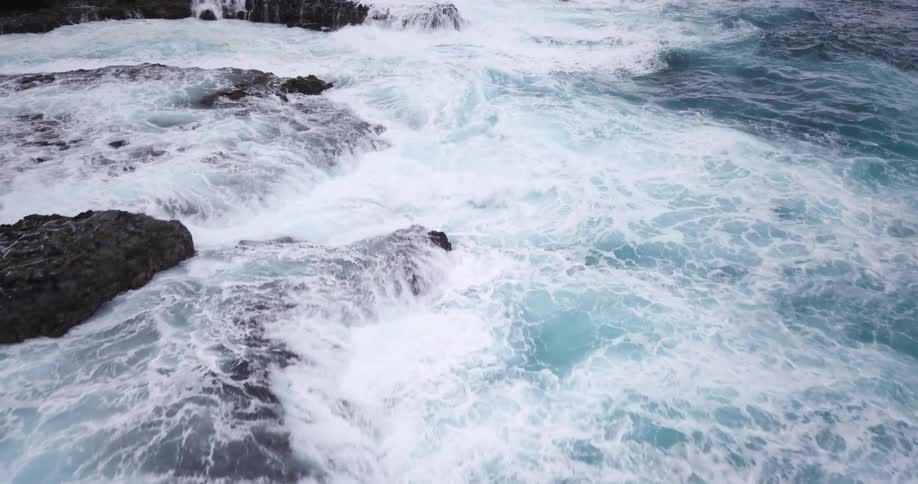 Waves crash against black rocks