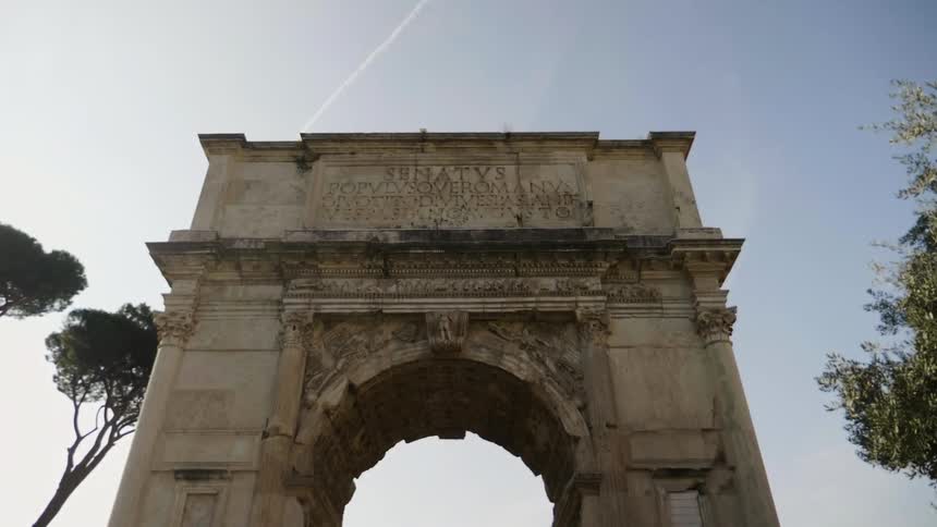 A large stone arch has engravings at the top on a cloudy day