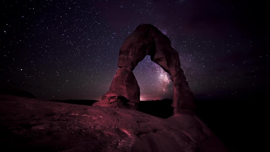 The stars move fast over the stone archway on the mountain