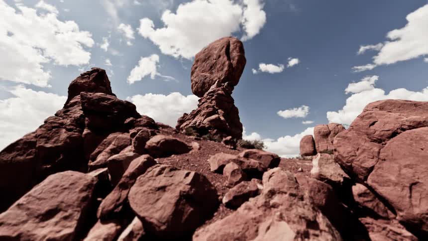 White clouds flow over a rocky desert landscape during the day