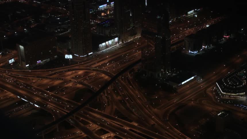Cars drive on a city highway system at night