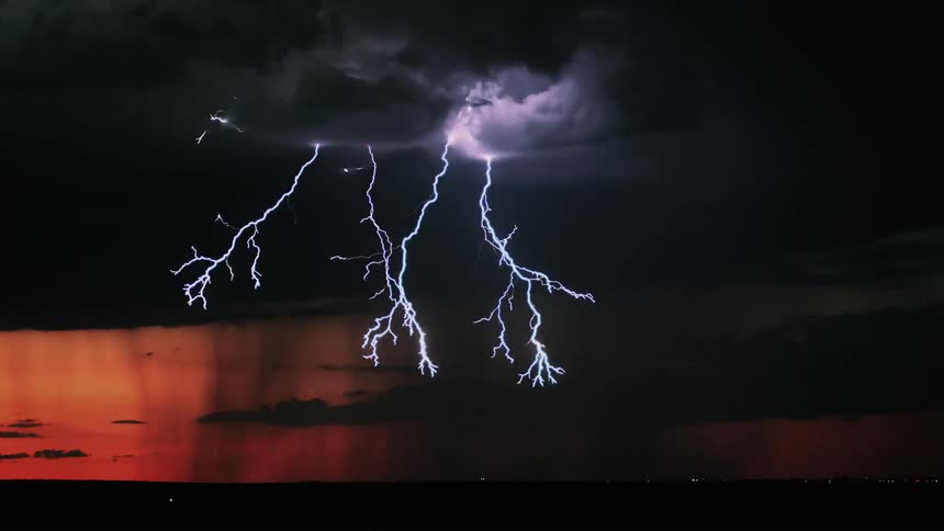 Rain is pouring down heavy with lightning in the dawn clouds