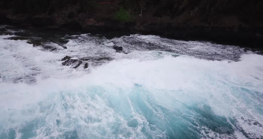 Waves break and foam against the rocks