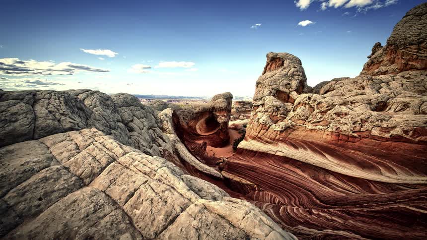 Clouds float over rock formations in a desert
