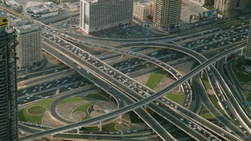 People drive around a large highway through the city below