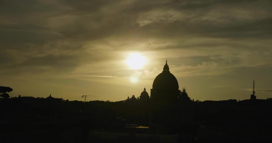 The sun shines behind a domed building