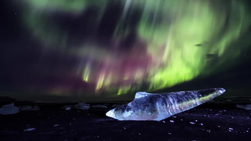 The shore has ice all over and the sky is full of flares