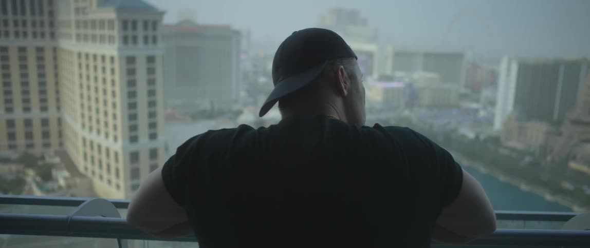 Man looks over a balcony at the city view