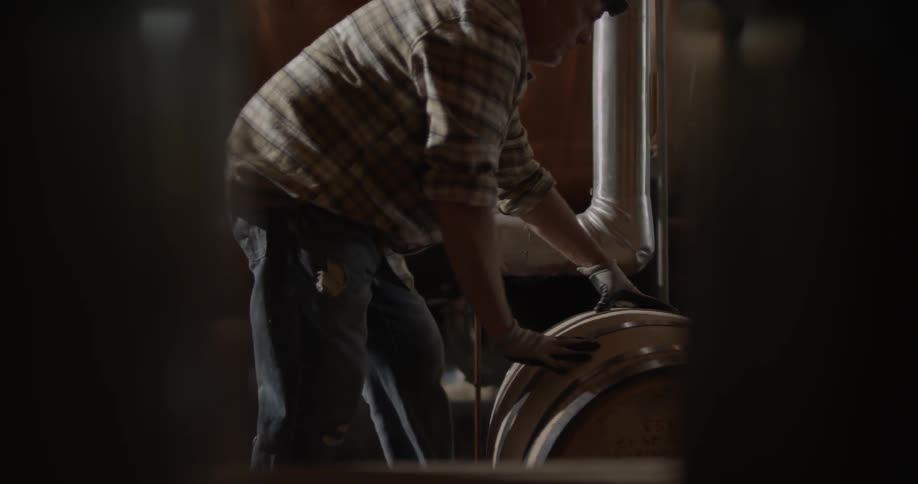 A man pushes a barrel past a pipe