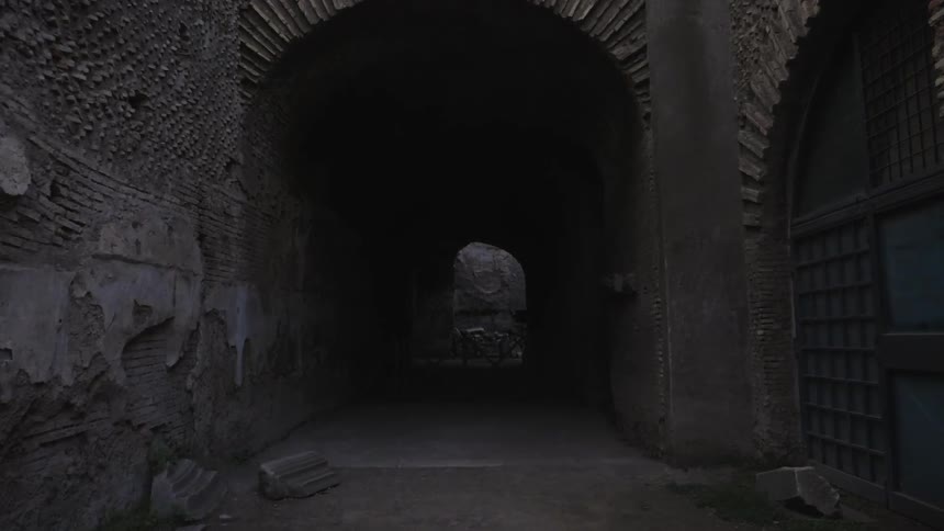 Shadows obscure the interior of an arched tunnel in an old building complex
