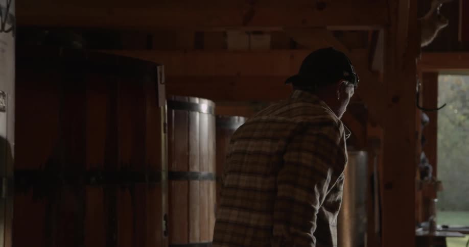 A man lifts a large glass vial out of a barrel