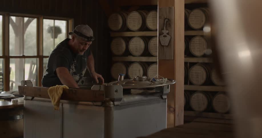 A man lifts a still lid and moves it over