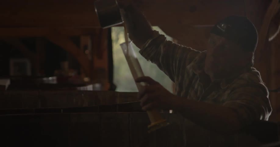 A man uses a pot to pour beer into a vial
