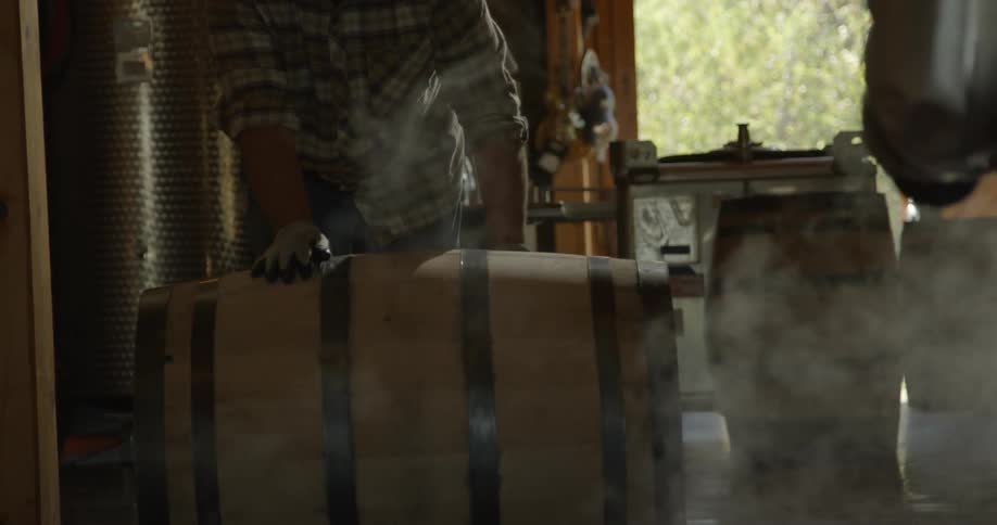 Person wearing gloves rolls a wooden barrel