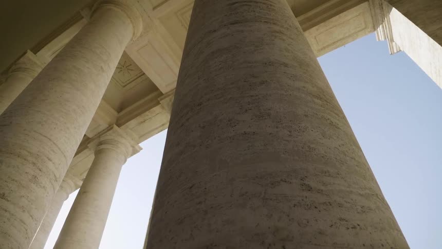 The sun shines between two rows of marble columns during the day