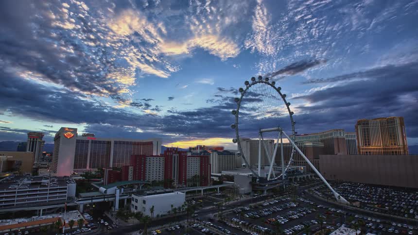 Clouds pass over city buildings and a ferris wheel
