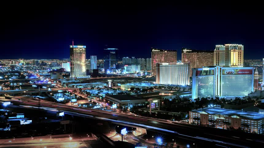 Cars travel on a highway past a city at night