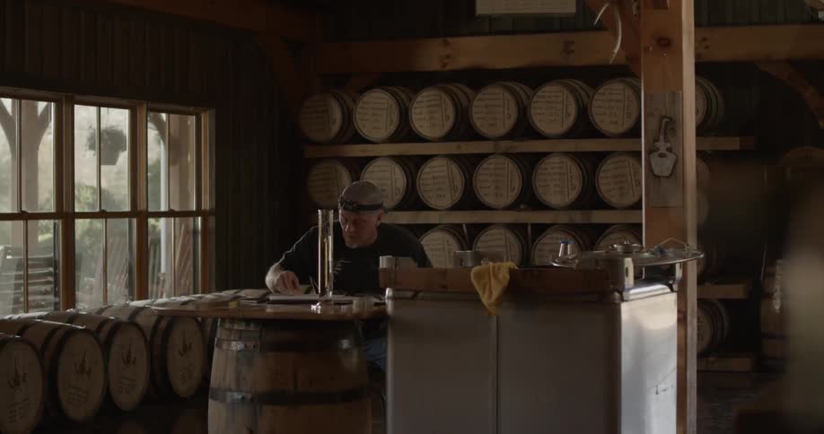 A man is writing at his desk in a distillery