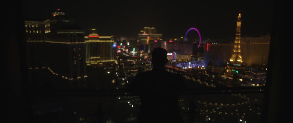 A person stands on a balcony overlooking las vegas at night